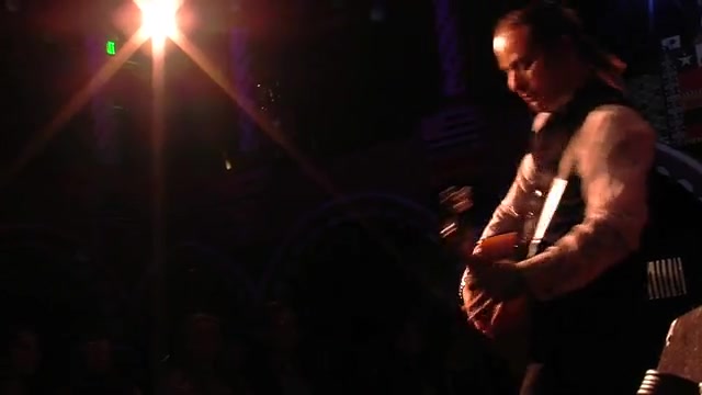 David Maldonado performing live on stage under a spotlight, playing acoustic guitar in a dark venue