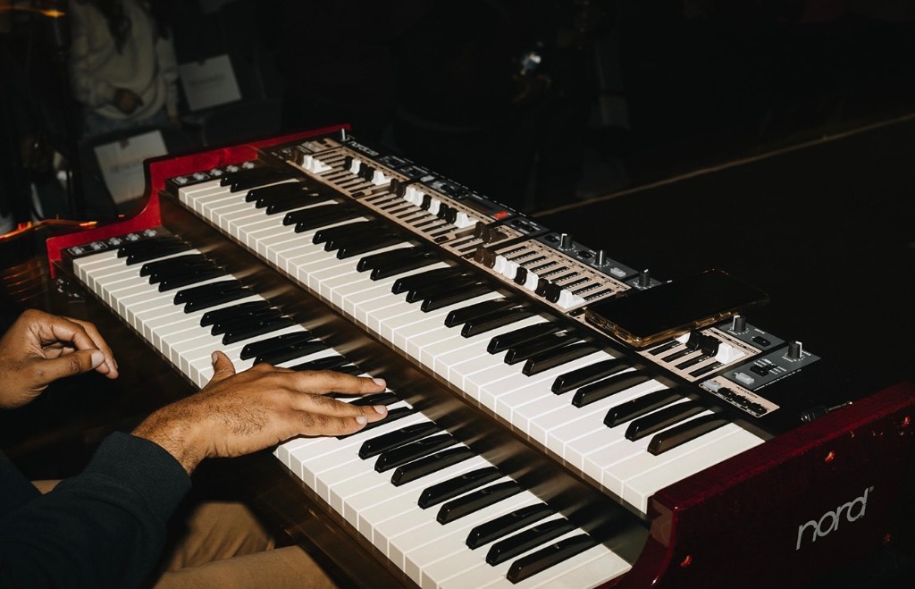 Hands playing a red Nord combo organ at a live show
